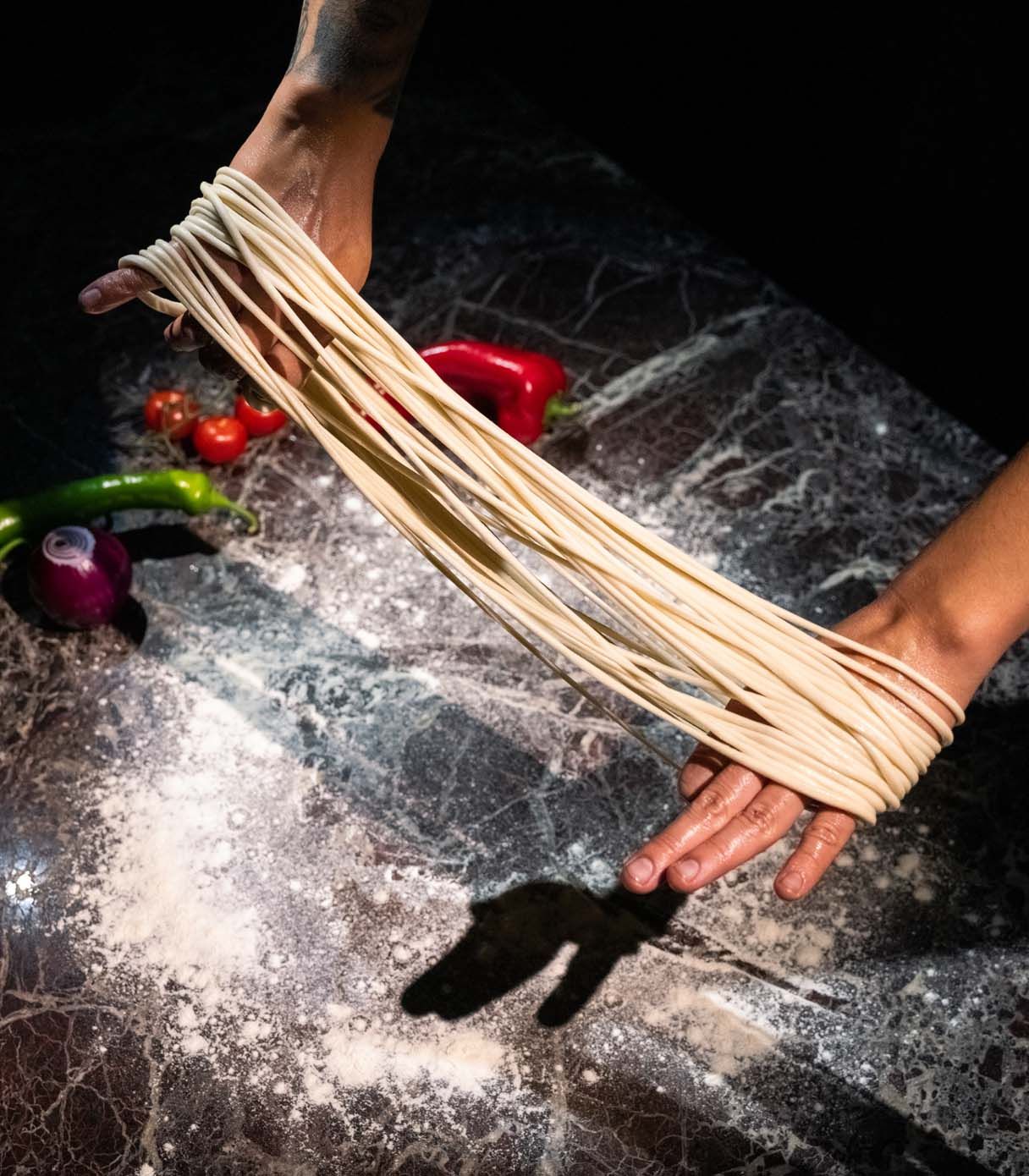 Freshly hand-pulled noodles being stretched in the Karamay kitchen